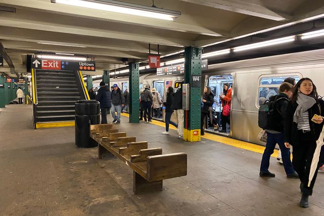 Photograph of wooden subway bench, with arm rests, that had its back removed, at the West 4th Street station